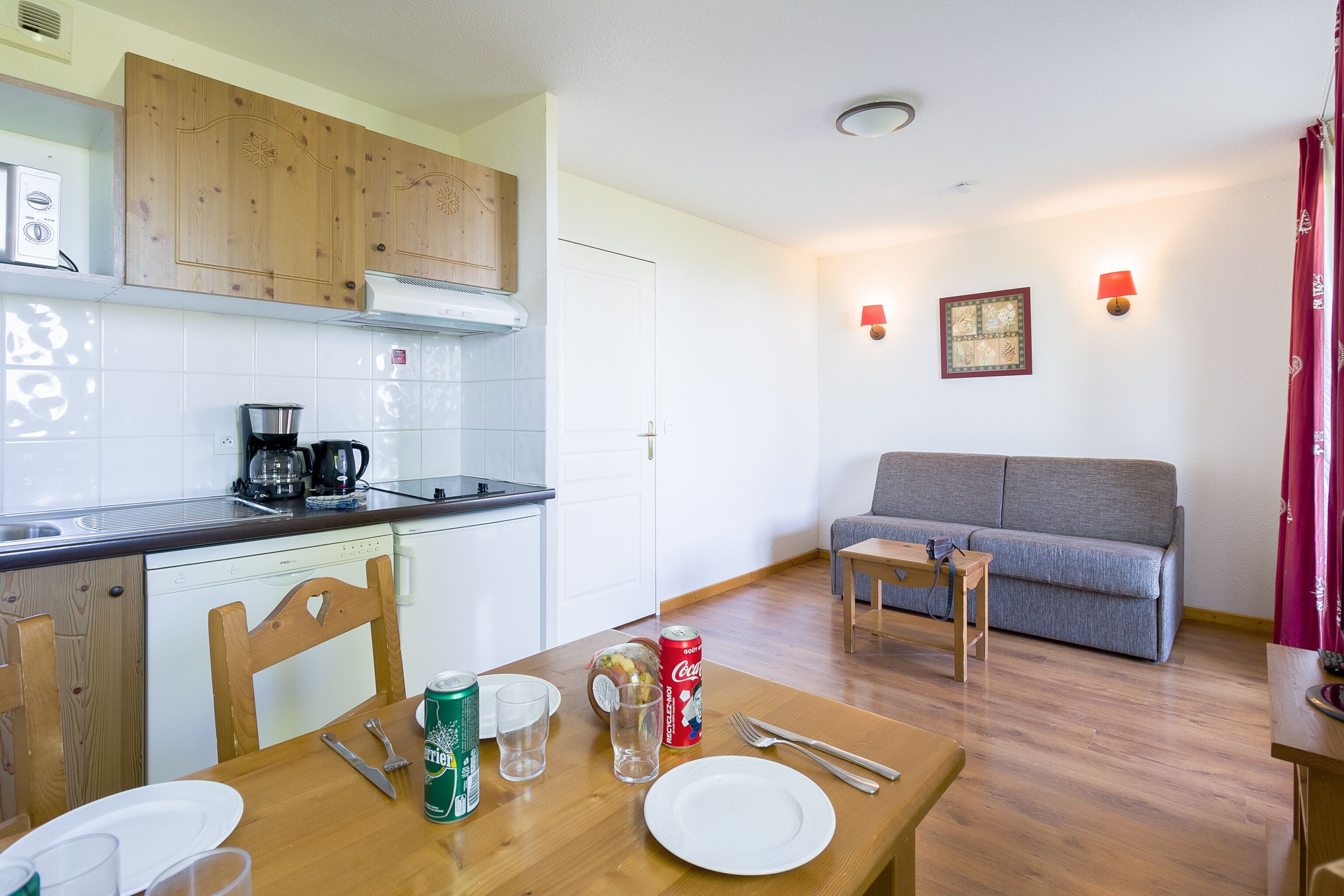 A compact living space with a kitchenette, dining area, and a grey sofa.