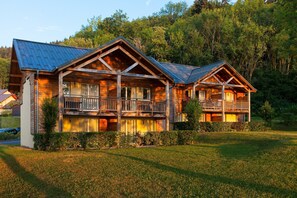 A log cabin with a balcony and a covered porch, surrounded by a well-maintained lawn and dense forest. - Garden & City Evian Lugrin (Lugrin)