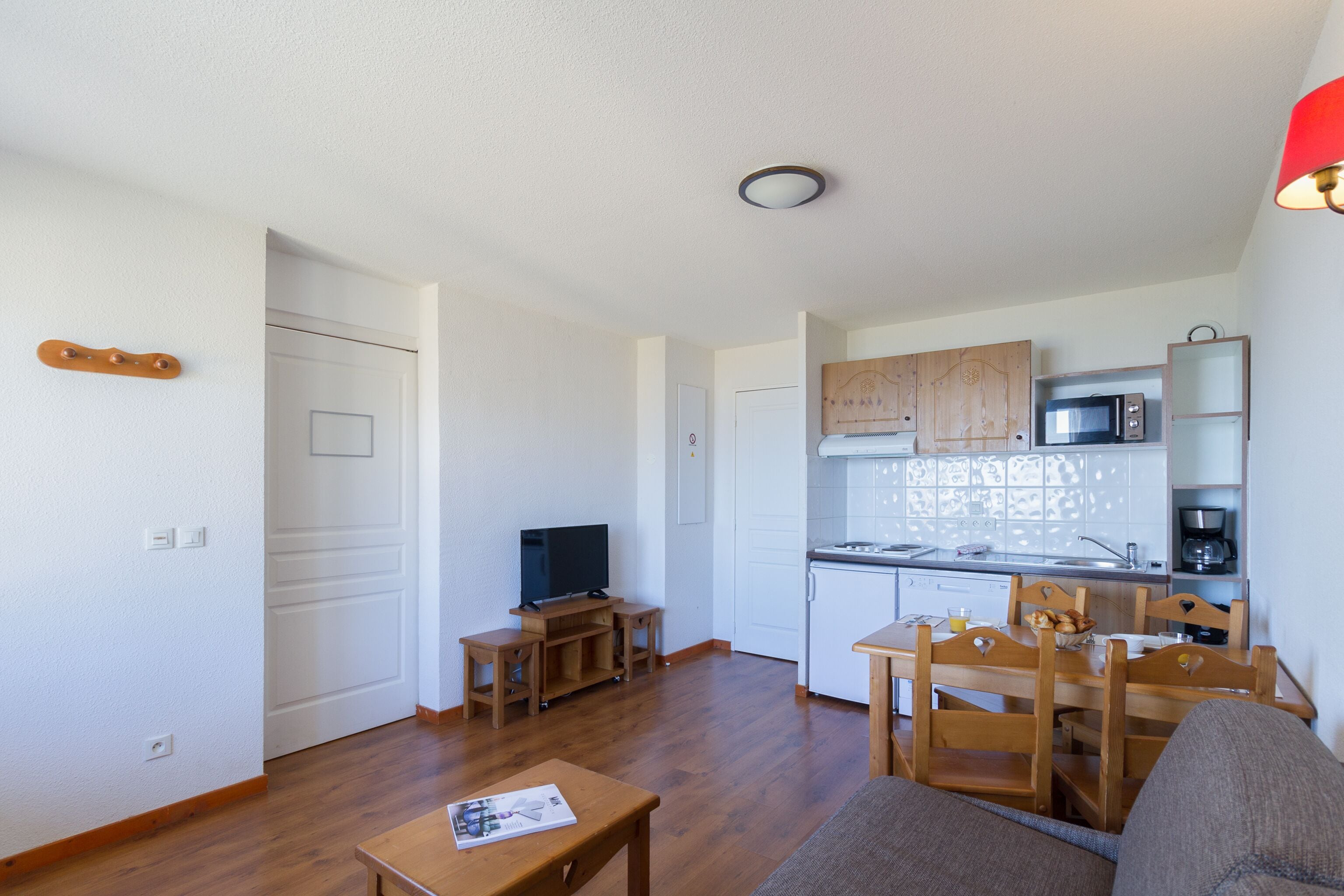 A compact living space with a kitchenette, a dining area, and a television.