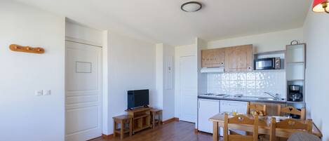 A compact living space with a kitchenette, a dining area, and a television.