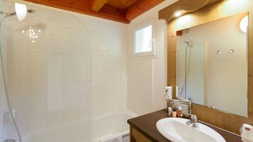 Une salle de bain avec une baignoire, un lavabo, un miroir et une fenêtre.