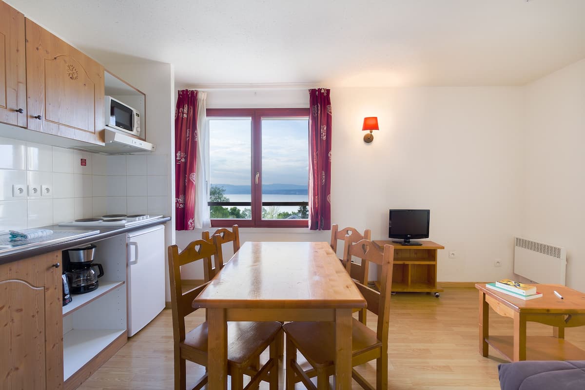 A compact kitchen with a dining area, a TV, and a view of the outdoors.