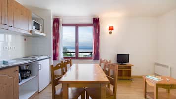Eine kleine Küche mit Essbereich, einem Fernseher und Blick ins Freie.