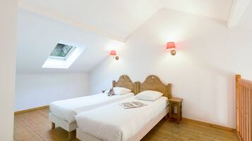 Ein Schlafzimmer mit zwei Einzelbetten, einem Oberlicht und zwei Wandlampen.