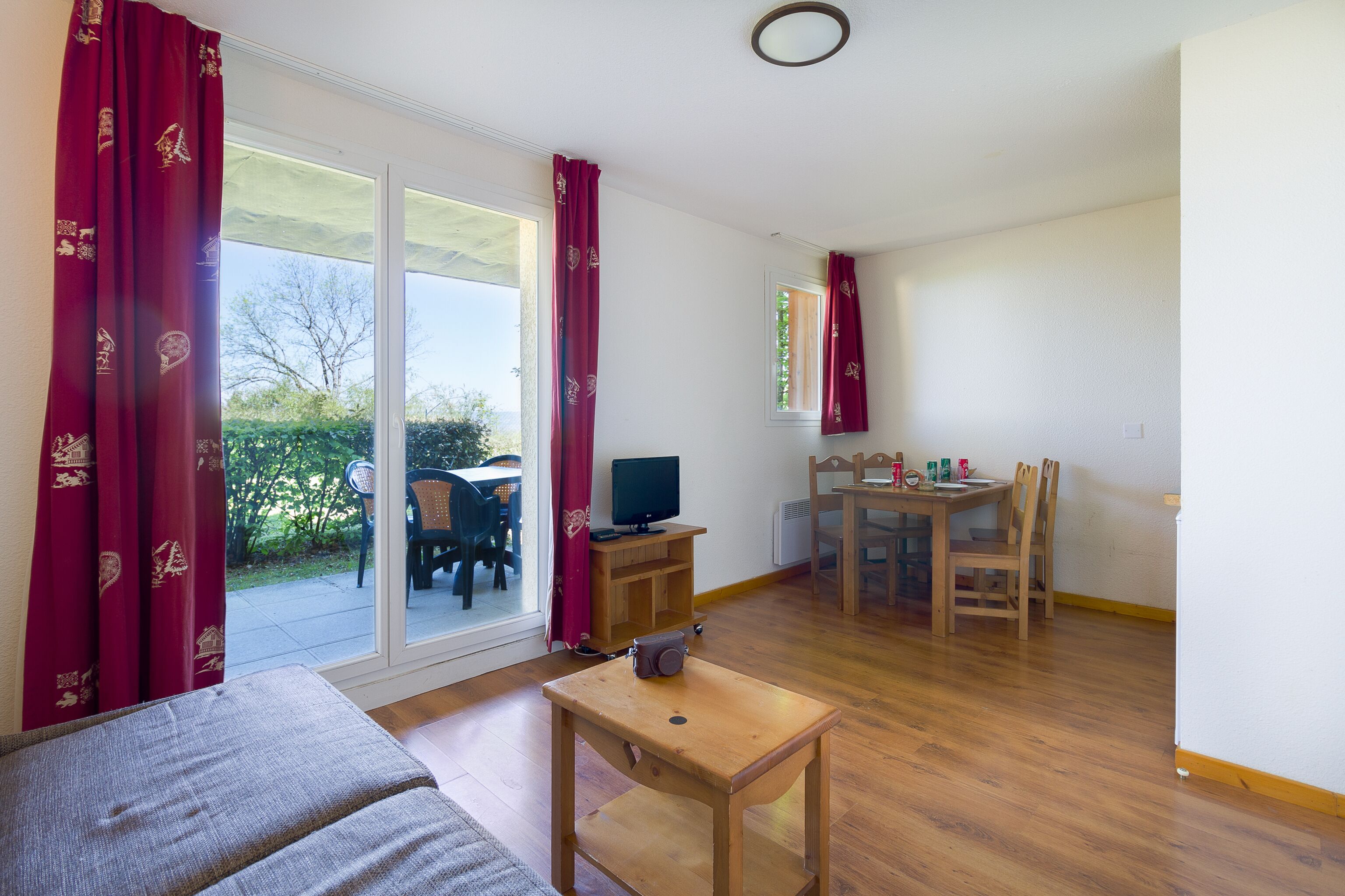 Ein Zimmer mit einer Couch, einem kleinen Tisch, einem Fernseher und einem Essbereich mit Stühlen und Tisch.