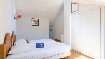 A bedroom with two single beds, a red wall lamp, a framed picture, and a sliding door.