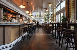 A bar area with wooden flooring, bar stools, and hanging lights. - Boundary Shoreditch (London)