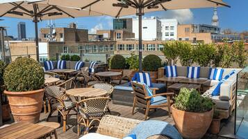 An outdoor seating area with wicker furniture, potted plants, and umbrellas.
