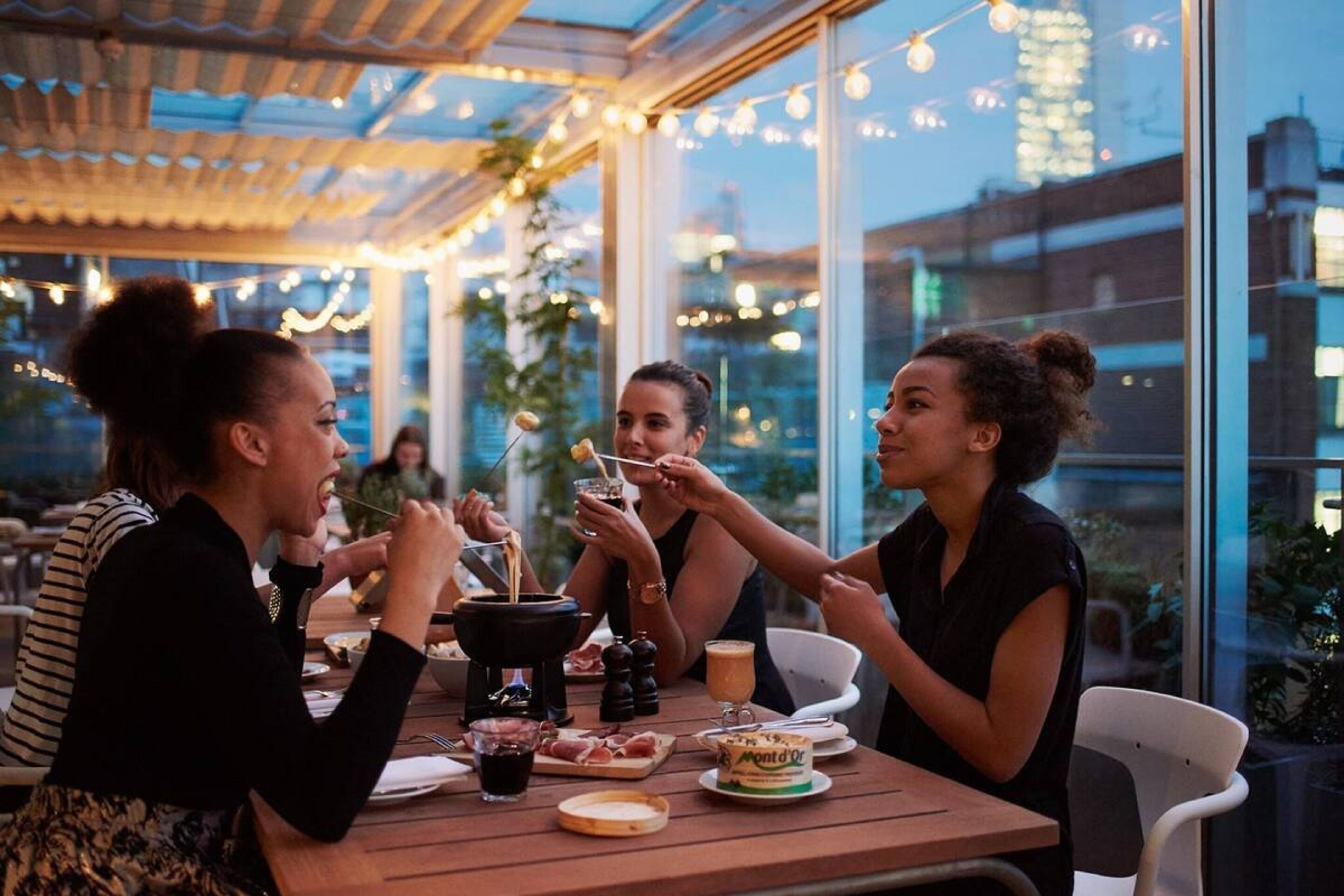 Un espace de restauration en plein air avec une table dressée pour quatre personnes, un réchaud et une variété de plats.