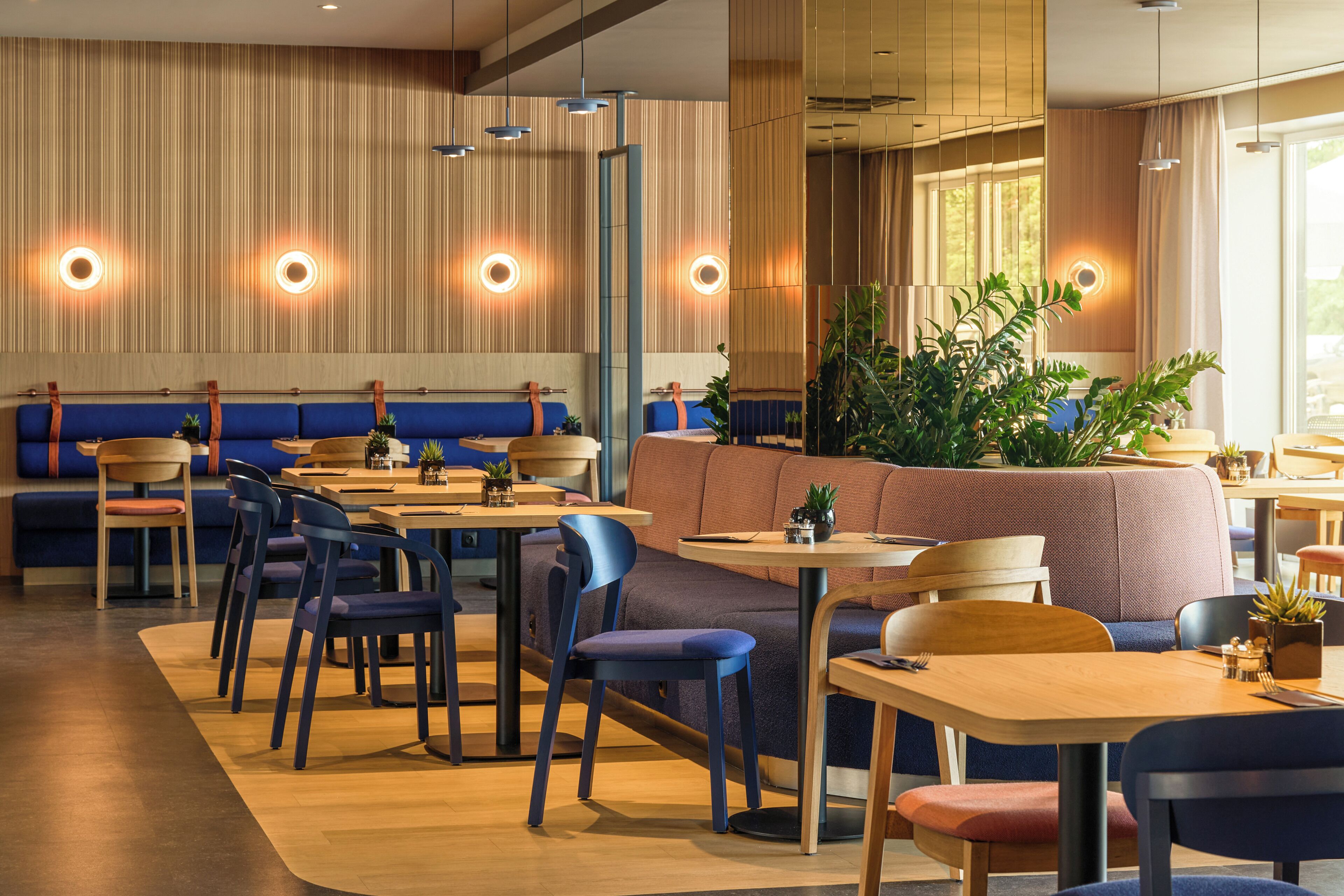 A restaurant with booths, tables, chairs, and pendant lighting.