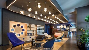 A modern lobby with multiple seating areas, a reception desk, and a variety of decorative wall elements.
