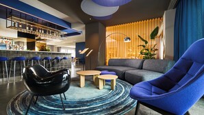 A modern lounge area with a bar, seating, and a large window with curtains.