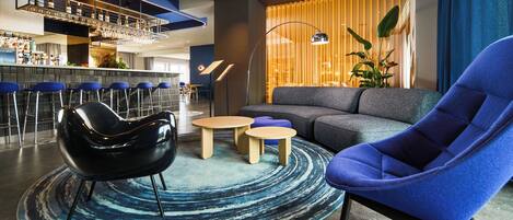 Un área de lounge moderna con bar, asientos y un amplio ventanal con cortinas.