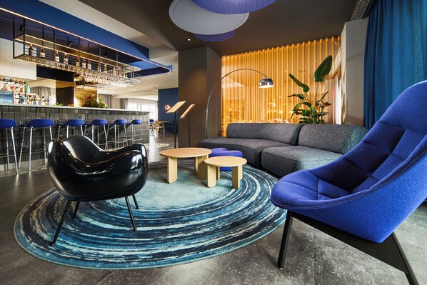 Un área de lounge moderna con bar, asientos y un amplio ventanal con cortinas.