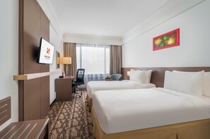 A hotel room with two beds, a desk, a chair, a TV, and a window with curtains.