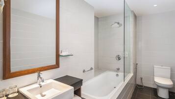 A modern bathroom with a white sink, a glass-enclosed shower, and a toilet.