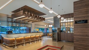Un área de bar moderna con una barra de madera, varios taburetes e iluminación colgante.