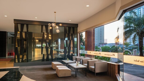 Un lobby moderno con áreas de descanso, una araña y ventanas amplias que ofrecen vistas de la ciudad.