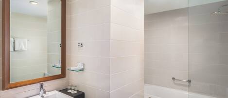 A modern bathroom with a sink, mirror, and glass-enclosed shower.