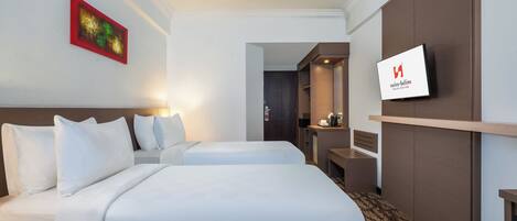 Una habitación de hotel con dos camas, un televisor, un cuadro y un espejo.