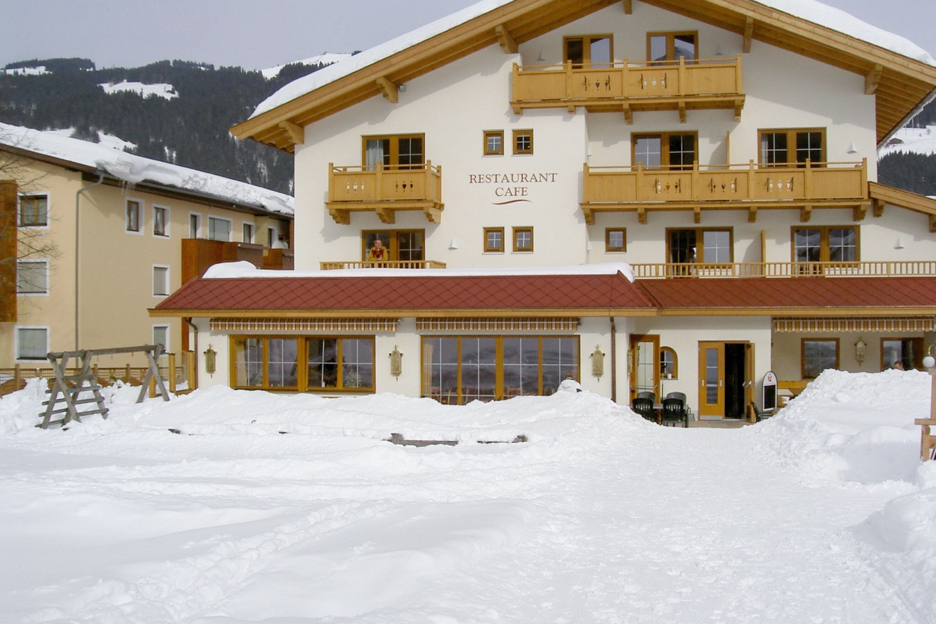 A restaurant cafe with a red roof, wooden balconies, and a snow-covered landscape.