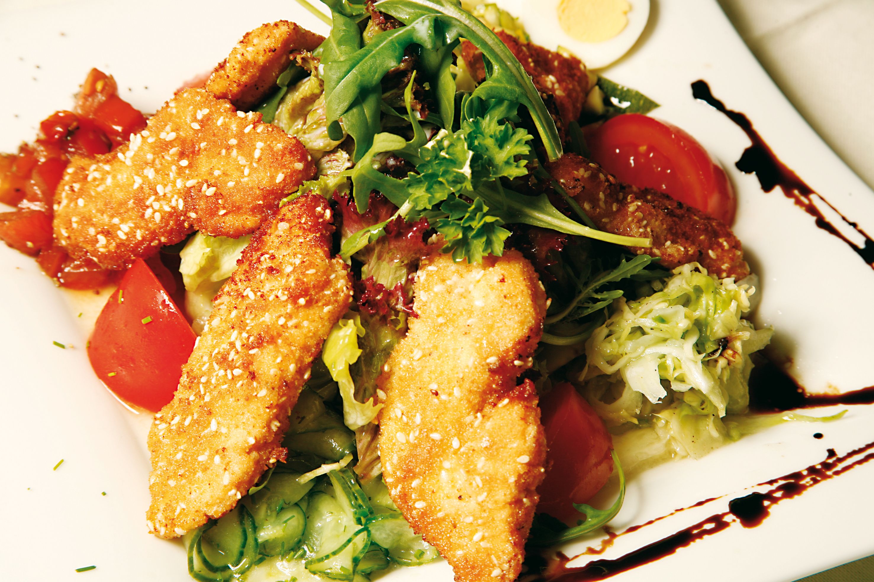 Un plato de comida con pollo empanizado, lechuga y tomates.