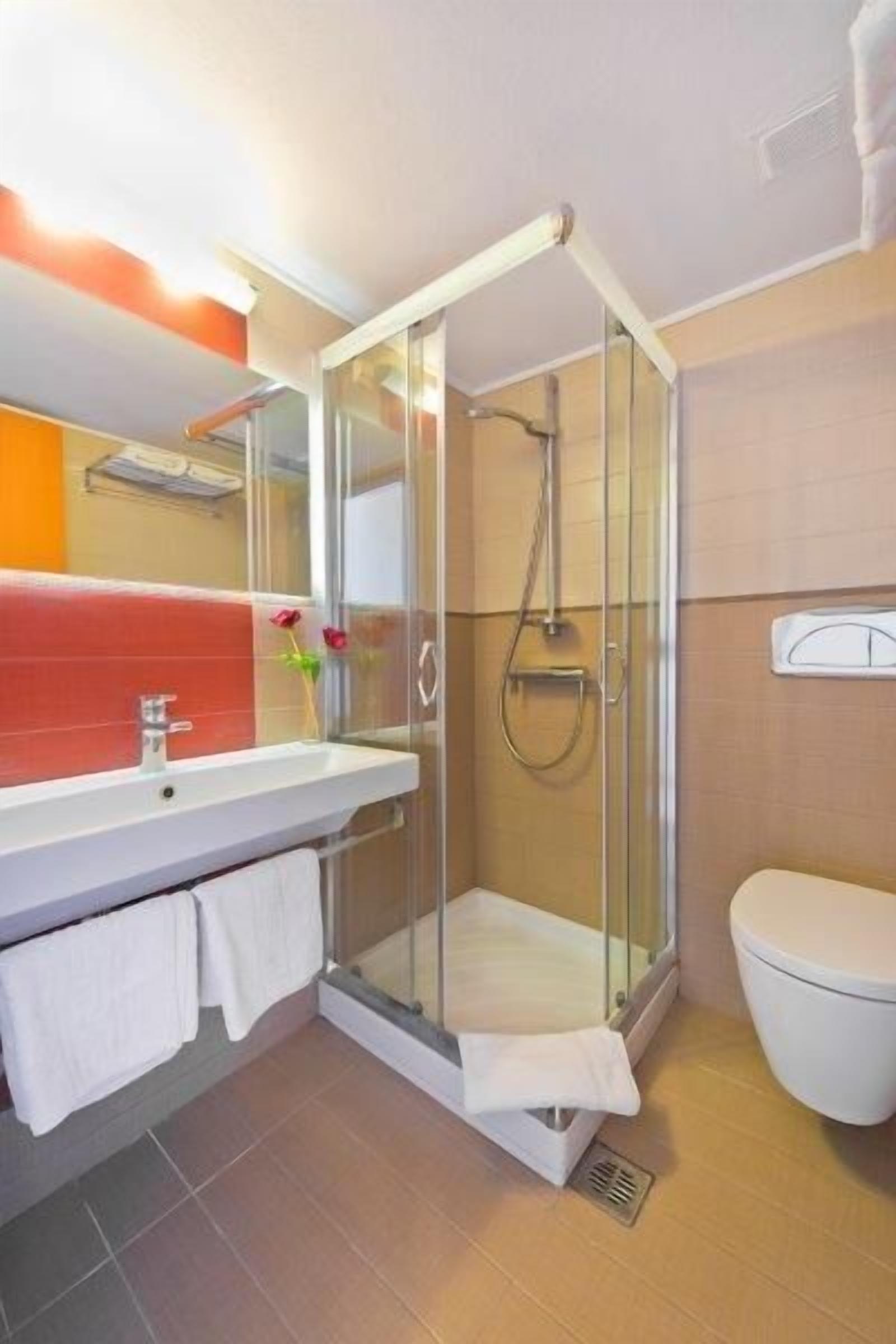 A modern bathroom with a glass shower enclosure, a white sink, and a toilet.