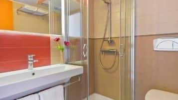 A modern bathroom with a glass shower enclosure, a white sink, and a toilet.