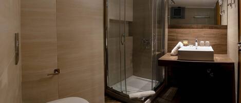 A modern bathroom with a glass-enclosed shower, a toilet, and a sink with a mirror above.