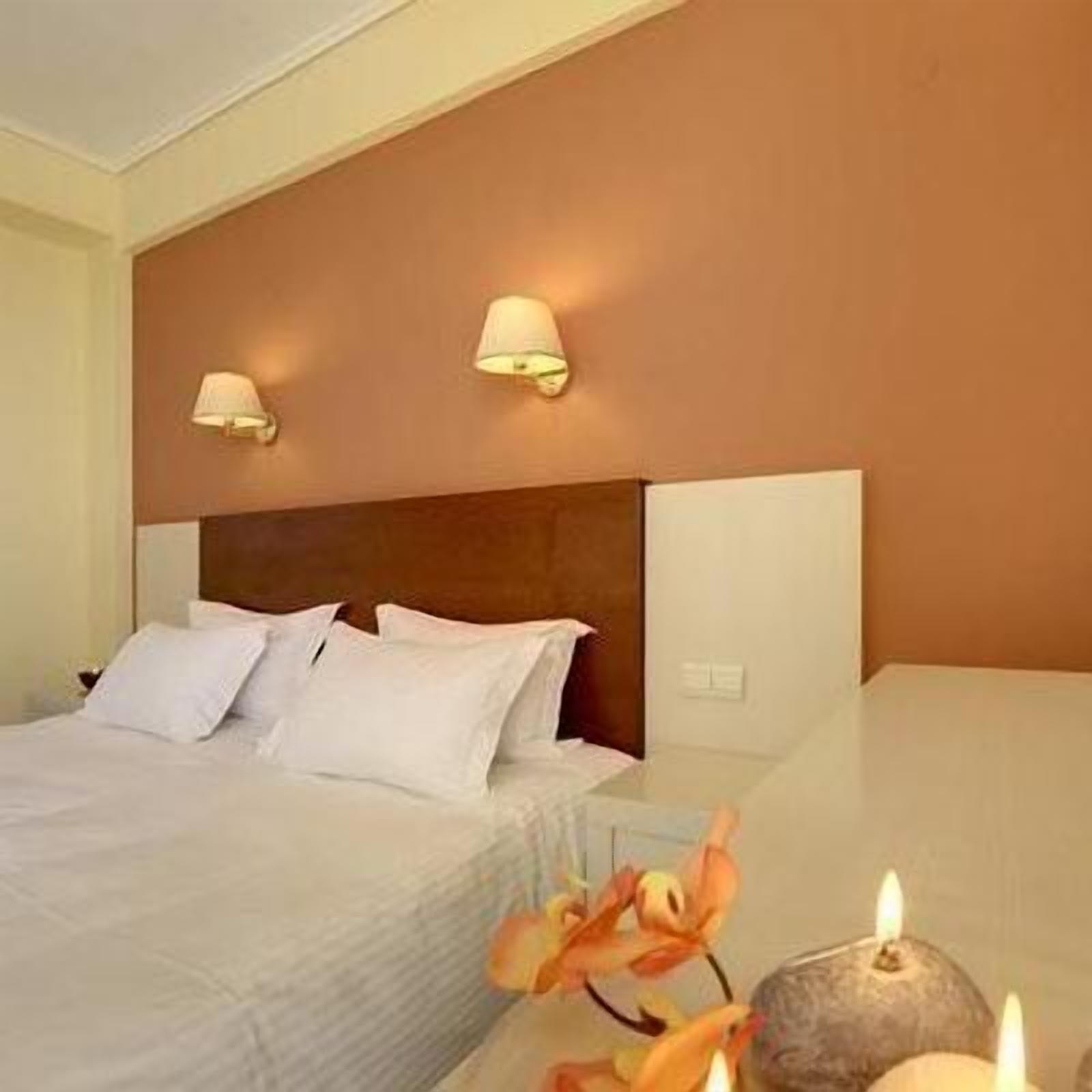 Ein Hotelzimmer mit einem Bett, zwei Wandlampen und einer Blumenvase.