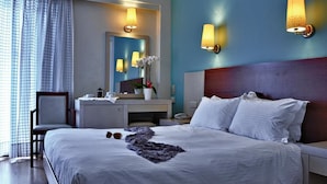 Een hotelkamer met een groot bed, een bureau, een stoel en een spiegel in de badkamer.