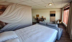 Habitación de hotel con una cama grande, un sofá, un escritorio y un televisor.