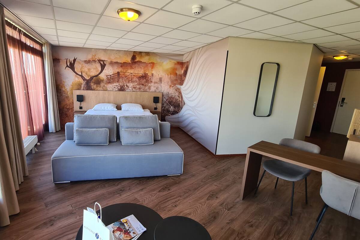 Een moderne hotelkamer met een groot bed, een bureau en een zithoek.