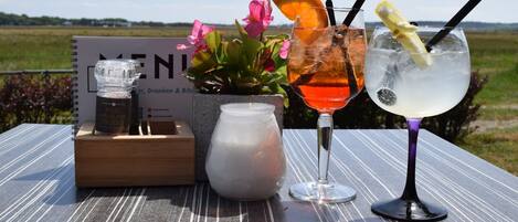 A table with drinks, a menu, and a candle.