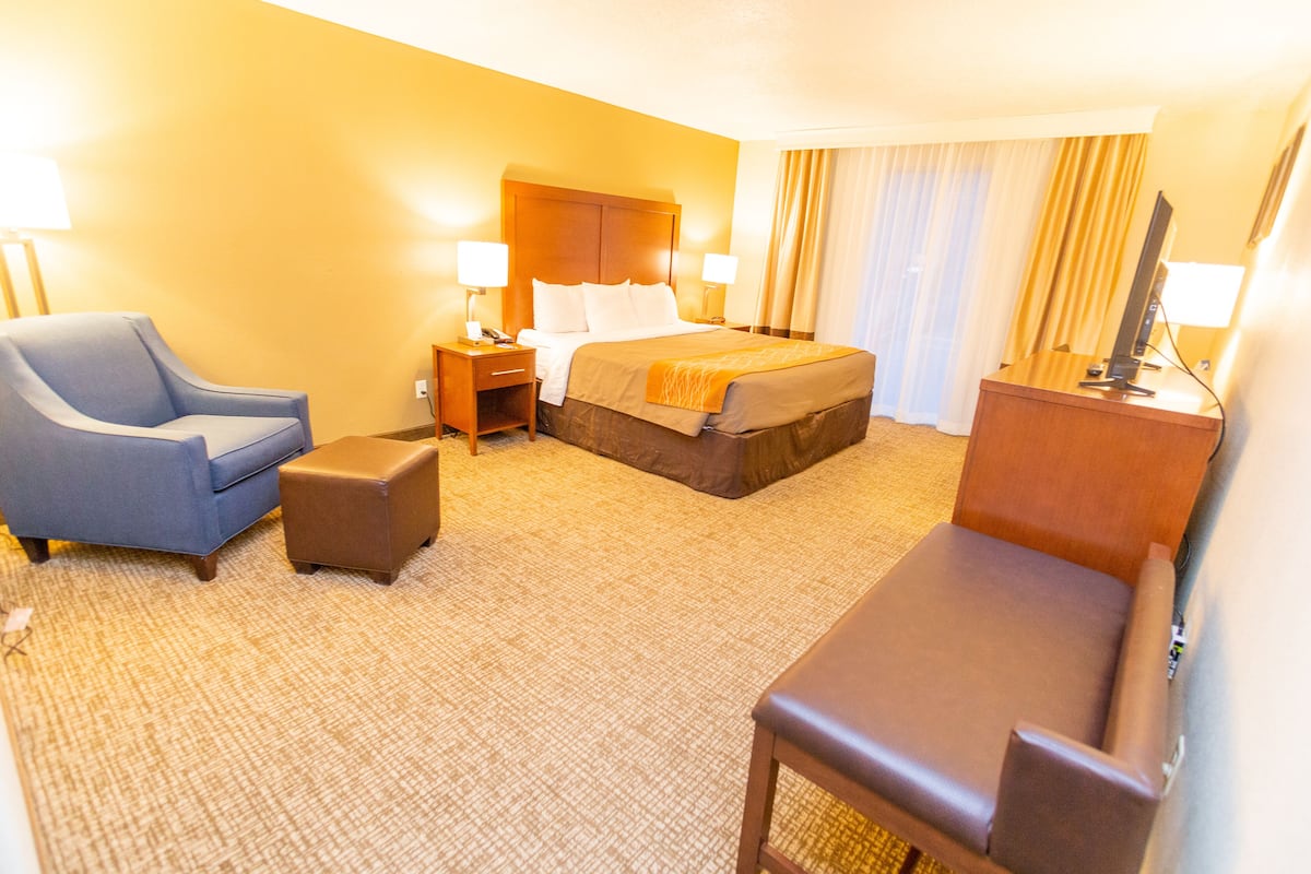 A hotel room with a bed, a desk, a chair, and a TV.