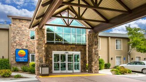Der Eingang eines Comfort Inn Hotels mit einer Steinfassade, großen Glasüren und einem überdachten Zugang.
