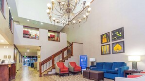 Eine geräumige Lobby mit einer Chandelier, einer Treppe, einem Empfangstisch und einem blauen Sofa.