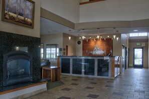 A reception area with a fireplace, a reception desk, and a sign for Allington Inn & Suites.