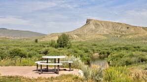 A picnic table in a natural setting with a mountain in the background. - Allington Inn & Suites (Kremmling)