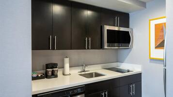 A modern kitchen with dark cabinets, a stainless steel microwave, a dishwasher, and a sink.