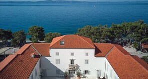 Situated by a large body of water, this charming building offers a serene view and a small garden area with potted plants.