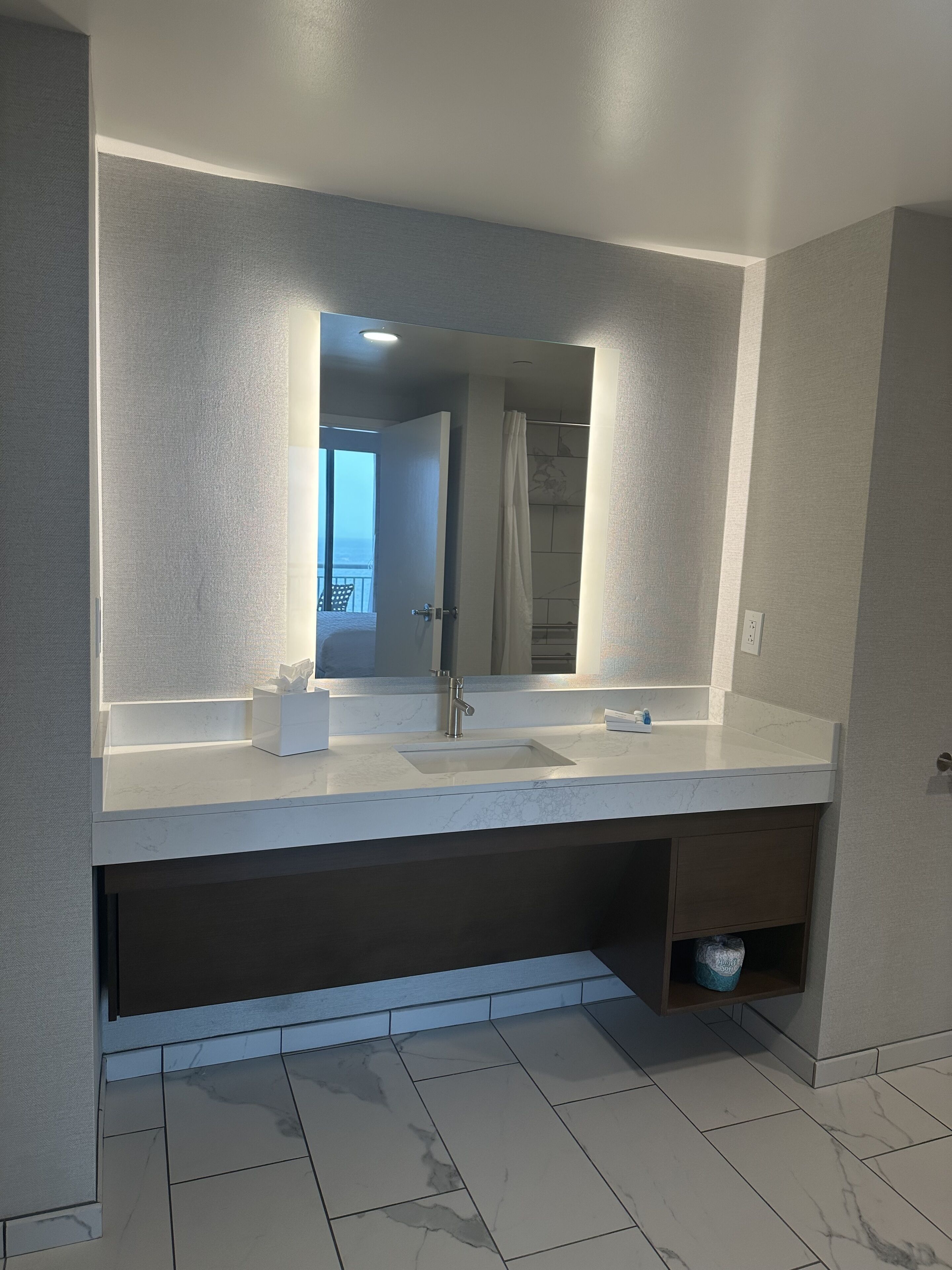 A modern bathroom with a large mirror, a sink, and a shower area.