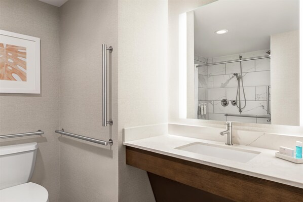 Un baño con lavamanos blanco, espejo y ducha.