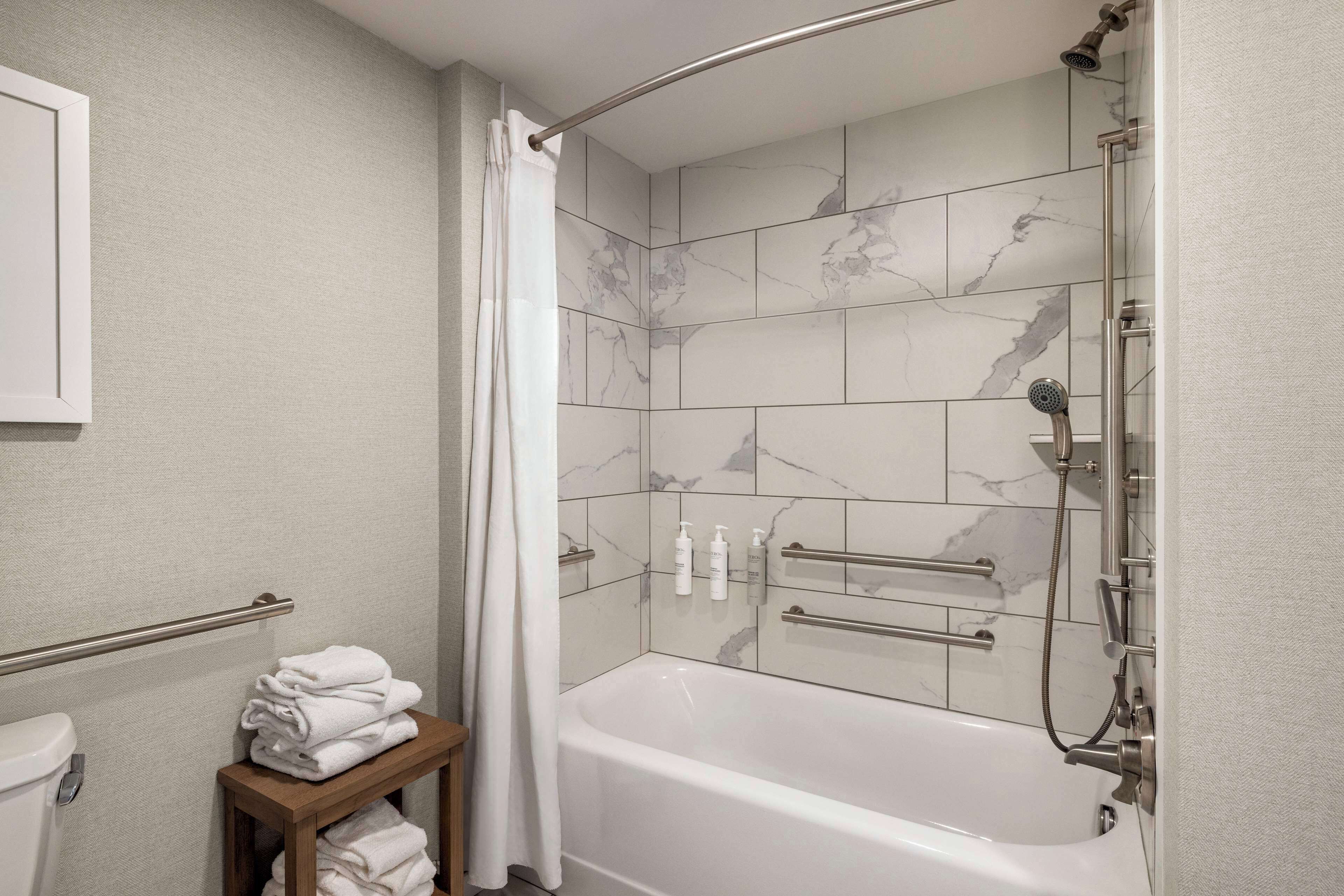 A modern bathroom with a bathtub, shower, and toilet.