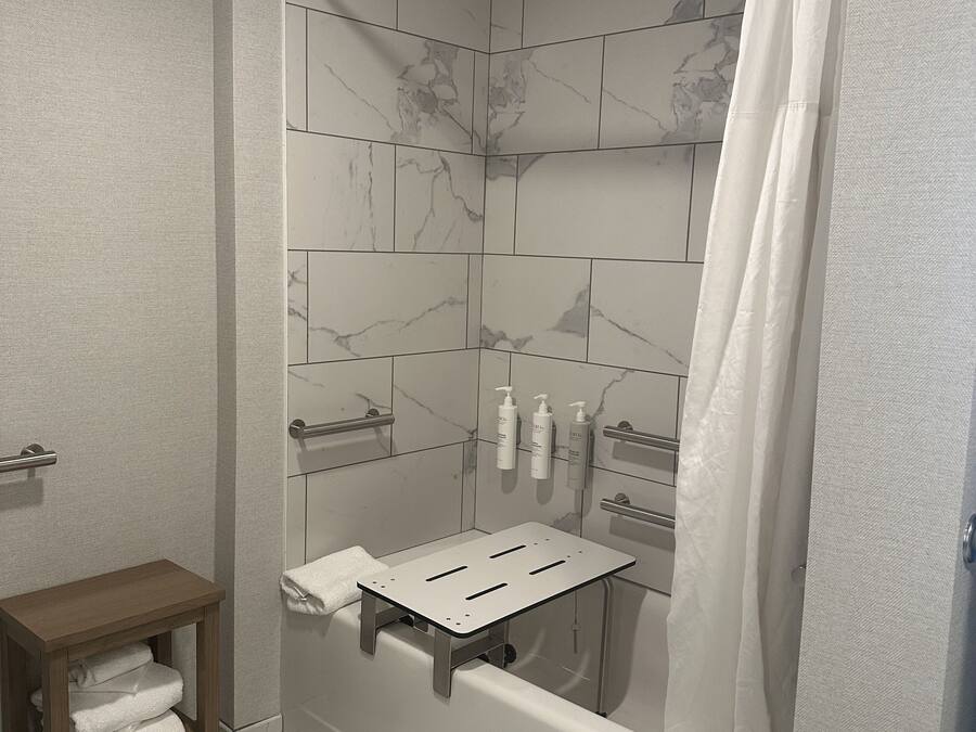 Een moderne badkamer met een douche, een bad en een houten plank met handdoeken.