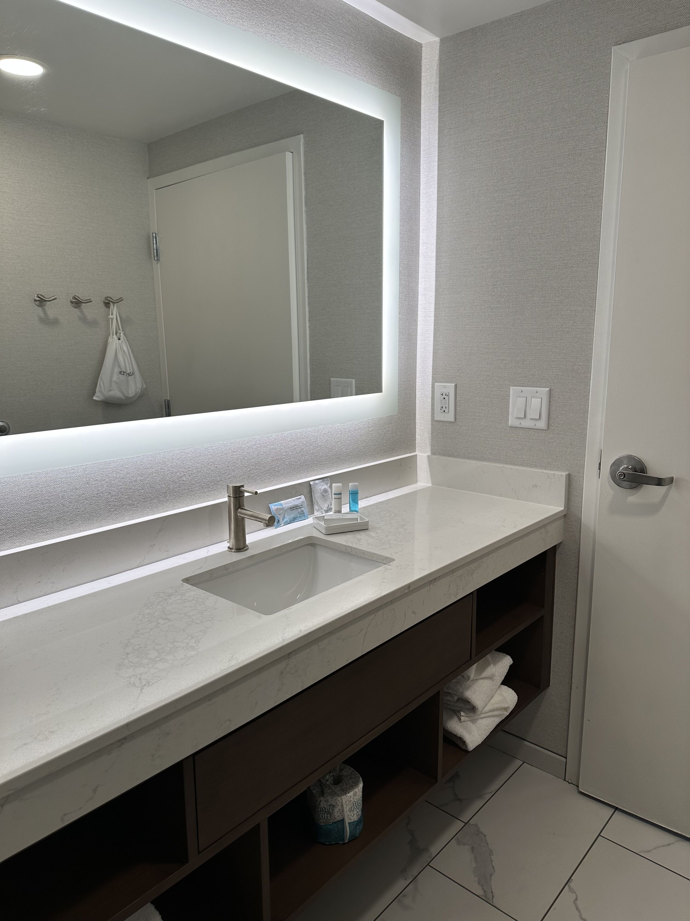 Une salle de bain moderne avec un grand miroir, un lavabo et un porte-serviettes.