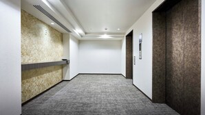 Corredor com parede de mármore, balcão de recepção e porta com painel texturizado.