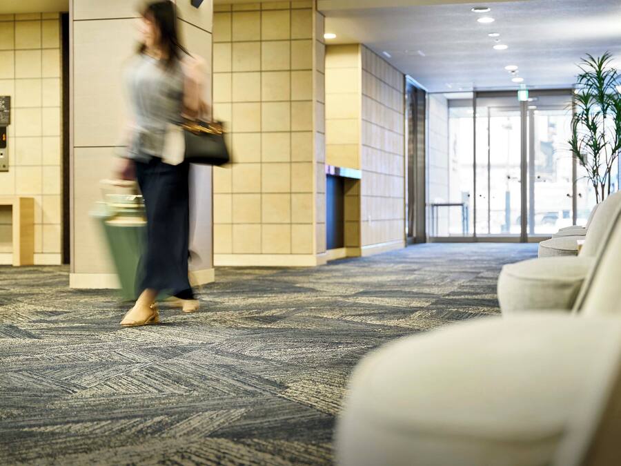 Vestíbulo de hotel con piso alfombrado, una recepción y un área de estar.