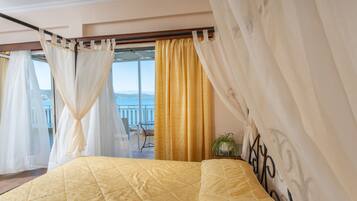 A bedroom with a large bed, curtains, and a view of the outdoors.