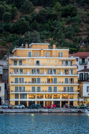 Un hôtel à plusieurs étages doté de balcons, avec un restaurant au rez-de-chaussée et une vue sur l’eau.